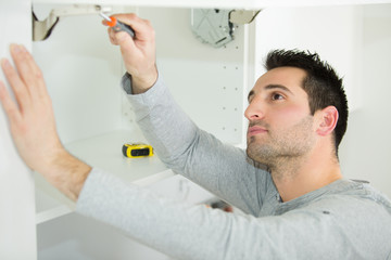 Fototapeta premium handyman fixing a door on the cupboard