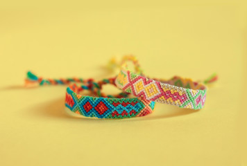 Two handmade homemade colorful natural woven bracelets of friendship isolated on wooden background, various colors