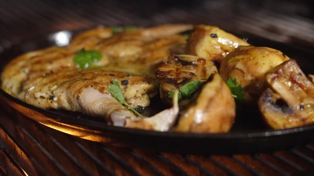 Tobacco chicken with mushrooms and potatoes, on a cast-iron platter on the grill