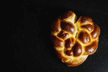 Heart-shaped challah bread on a dark surface