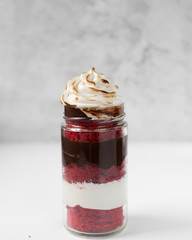 Red velvet cake in a jar with a chocolate and meringue filling and a toasted meringue topping