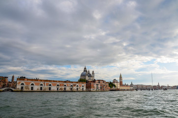 Looking back into Venice along the coastline from a water taxi boat in the cloudy sky