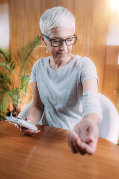 Senior Woman Doing Elbow Physical Therapy with TENS Electrode Brace Pads, Transcutaneous Electrical Nerve Stimulation