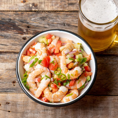 Mexican shrimp ceviche with tomato and serrano pepper on wooden background