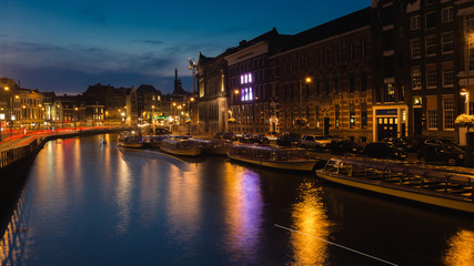 Amsterdam center at night. River and boats in the water.