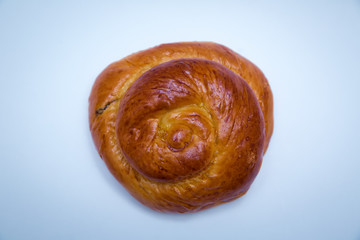 Freshly baked sweet bun with raisins isolated on white background, top view . Freshly baked sweet bun with raisins isolated on white background, top view . Fresh bake cinnamon roll with a cherry .