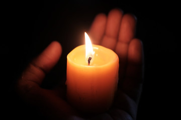 burning candle on women hand at night , close up 