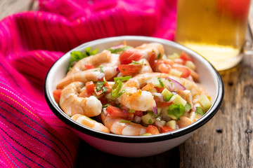 Mexican shrimp ceviche with tomato and serrano pepper on wooden background