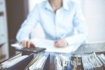 Binders of papers waiting to process by bookkeeper woman or financial inspector, close-up. Business portrait. Audit or tax concepts