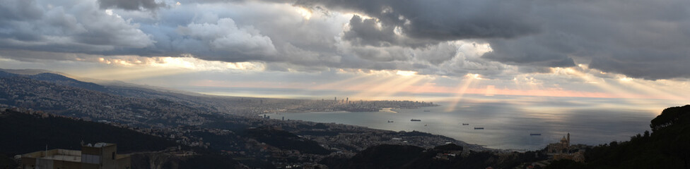 large panoramic view of Berut and Saint Georges Bay and lebanese shore between Beirut and Jounieh, shot from the mountain with dramatic sky and rays of light