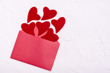 Valentine's Day. Red felt hearts fly out of an open red envelope on a white background. Copy space