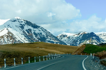 Fototapeta premium Caucasus mountains and road on a background of blue clouds..