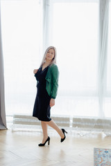 Obraz premium Blondie woman with long hair is posing in front of the window.