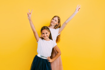 Mom and little daughter having fun, dancing and having fun on a yellow background