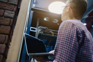 In the server room a technician/ It engineer/ hold the notebook