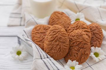 Fototapeta na wymiar Easter egg shaped ginger cookies on the kitchen towel background with glass of milk, selective focus