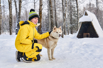 Fototapeta na wymiar woman stroking a husky dog in the winter forest