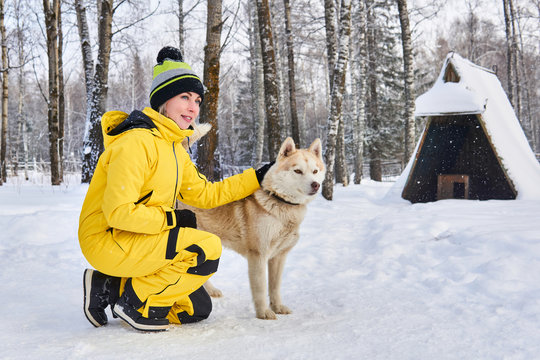 Woman Stroking A Husky Dog In The Winter Forest