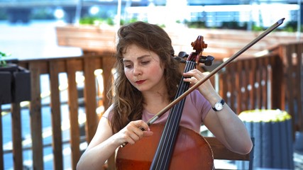 Female Musician Plays The Cello On Summer Terrace Outdoor