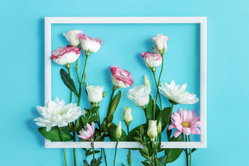 Composition, bouquet of pink and white flowers are lined under frame on blue background. Greeting card template, invitation for celebration, party. Happy mothers, women day, spring, easter concept.