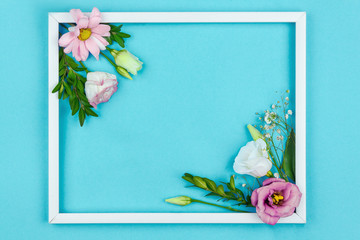 Composition of pink and white flowers are lined inside frame on blue background. Greeting card template, invitation for celebration, party. Happy mothers, women day, spring, easter concept.