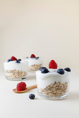 Yogurt with raspberry, blueberries and oat flakes with beige background