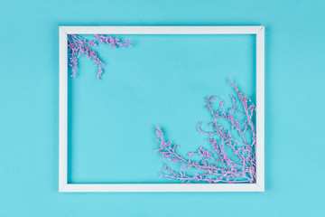 Composition of pink sprigs with leaves are lined inside white frame on blue background. Greeting card template, invitation for party, event. Happy mothers, women day, spring, easter concept.