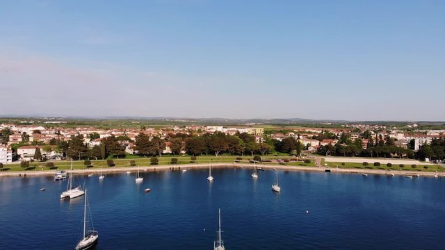 Yachts and boats in the water of the sea and a nice seaside town Umag in the background on a nice sunny day, Croatia