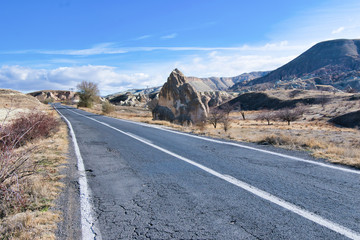 Asphalt countrysde road in Cappadocia, Turkey with no cars around and rock formations ion the background in a sunny day. Travel and road trip in Turkey.