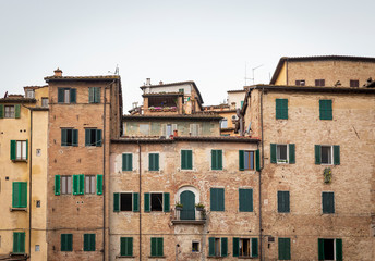Fototapeta premium a view of typical brown houses with green windows in Siena city, Tuscany, Italy