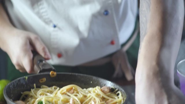 Chef throwing spaghetti pasta in a frying pan in a restaurant kitchen. Food ingredient. Cooking on cuisine. Cooked for gourmet. Prepare food to eat. Gastronomy culinary. Delicious dinner.