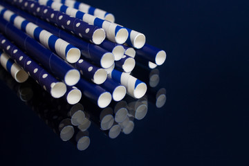 lots of blue paper tubes with white pea and cocktail strips lie on a mirrored dark background.