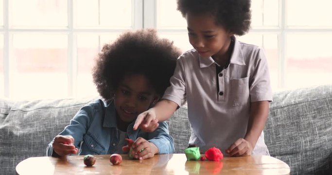 Two cute african children playing with playdough at home