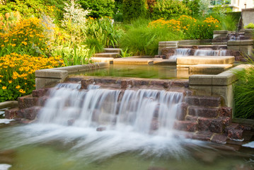 Naklejka premium The cascade of the silky water and yellow flowers in Downtown of Vancouver, Canada