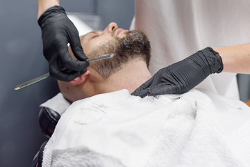 beard modeling in Barber shop, beard care for men, male beauty and care concept, shaving with a straight razor