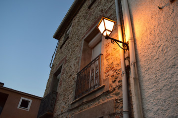 Fototapeta na wymiar A Wall Mounted Street Lamp on a Quaint House at Down