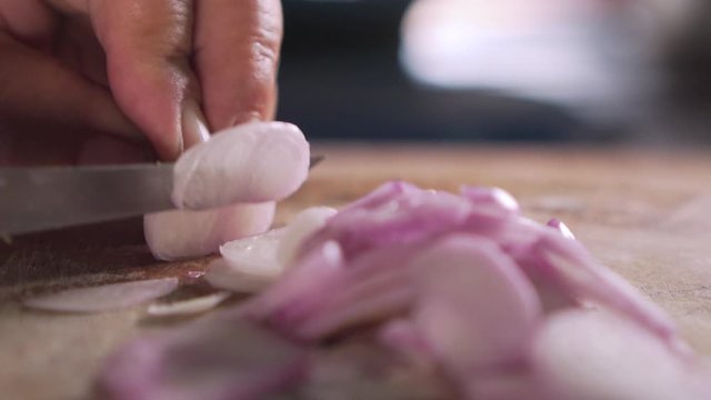 Lady chopping shallot on wooden board. Close up. Preparing for cooking. Slow motion.