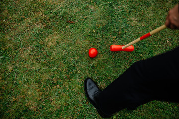 Top view of a game of croquet. In the frame, the player’s hands, the ball and the hammer.