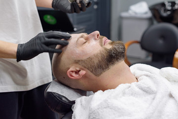 beard modeling in Barber shop, beard care for men, male beauty and care concept, applying the scrub to the face