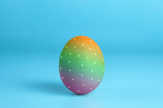 One bright rainbow painted easter egg on blue surface. Colorful easter eggs decoration. Copy space for text.