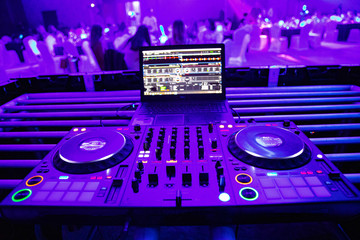 Fototapeta na wymiar DJ plays live set and mixing music on turntable console at stage in the night club. Disc Jokey Hands on a sound mixer station at club party. DJ mixer controller panel for playing music and partying.