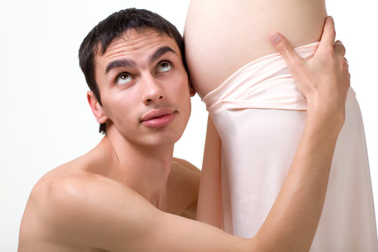 Happy young man future father listens to the movements of his child in the stomach of a pregnant woman. The concept of expectation of the first-born and fatherly unrest