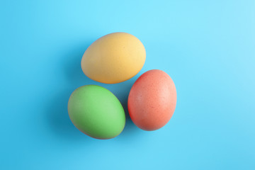 Top view of three bright painted easter eggs on blue surface. Colorful easter eggs decoration. Flat lay, top view. with copy space for text.