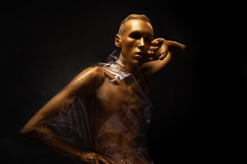 Fototapeta na wymiar Man in gold paint. Guy fashion model beauty shot Shiny body art paint gold on a black background.