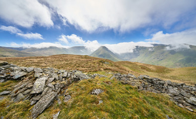 Fototapeta na wymiar Scenic view of the mountain summits of The Knott, High Street, Thornthwaite, Gray Crag and a cloud covered Stony Cove Pike on a sunny day in the Lake District UK.