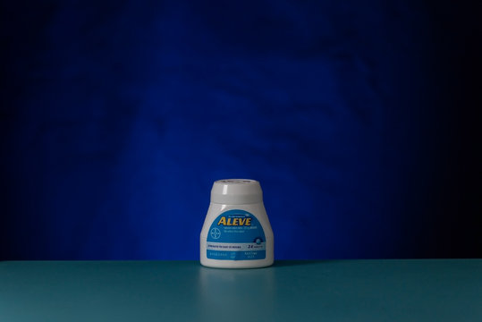 Bottle of Aleve against blue background, side view 
