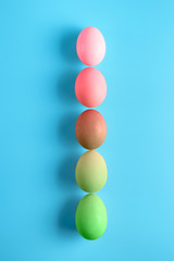 Top view of five bright painted easter eggs on blue surface. Colorful easter eggs decoration. Flat lay, top view. with copy space for text.