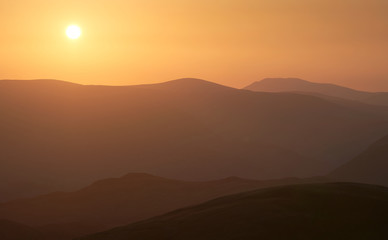 Late evening glow of sunset over the mountains of the Lake District UK from the summit of Rampsgill Head with The Knott just below.