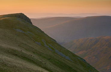 The summit of Kidsty Pike at sunrise with Long Stile to the right leading down to Riggindale valeey below in the Lake District UK.