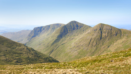 The three mountain summits of Yoke, Ill Bell and Froswick above Kentmere common and reservoir on a sunny morning in the Lake District UK.